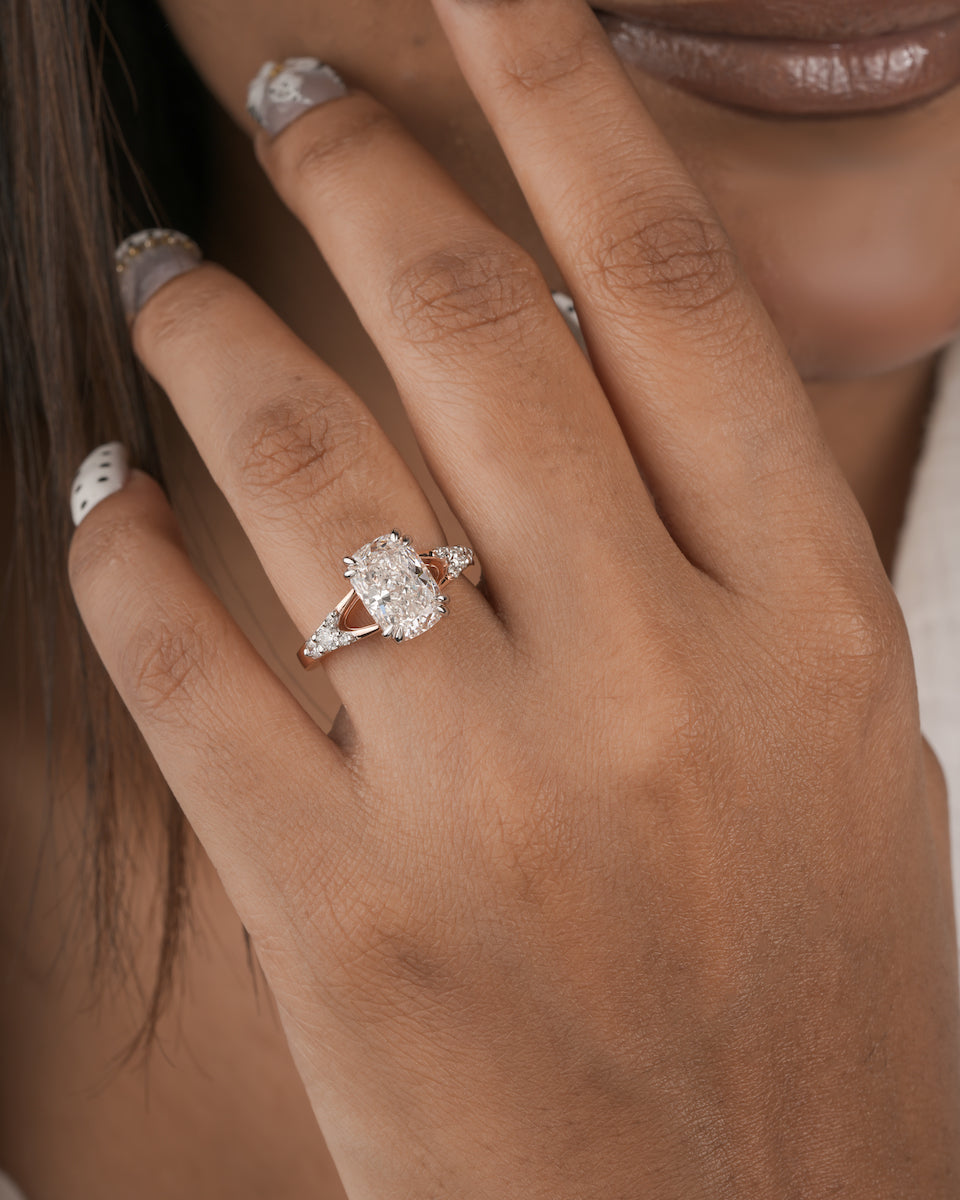 A close-up lifestyle shot of a woman's hand wearing a silver-toned diamond engagement ring with a marquise-cut center stone and smaller side stones.