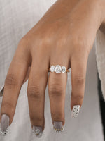 A close-up of a hand wearing a three-stone diamond engagement ring. The ring features three round brilliant-cut diamonds set in a yellow gold band.