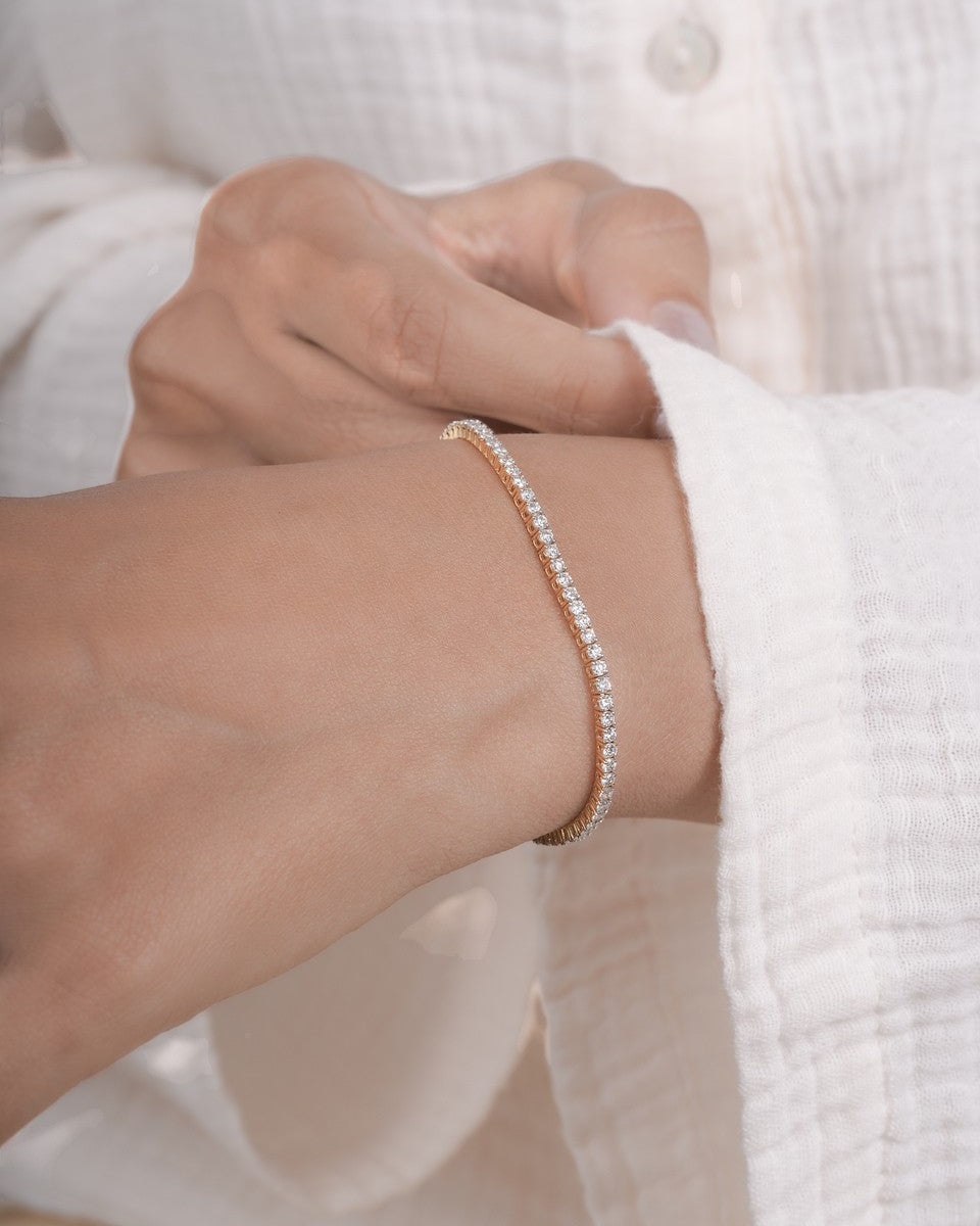 Close-up of a hand wearing a delicate bracelet with a blurred white background