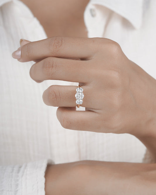 Hand wearing three stone diamond ring.