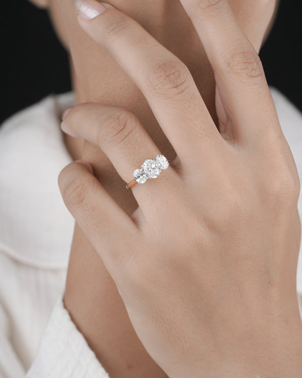 Hand wearing three stone diamond ring.