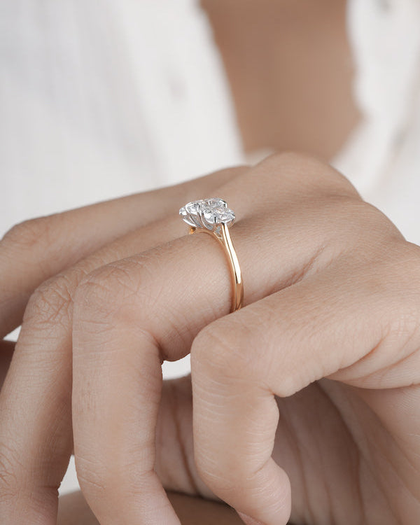 Hand wearing three stone diamond ring.