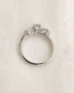 Three stone round cut diamond ring on a white background.