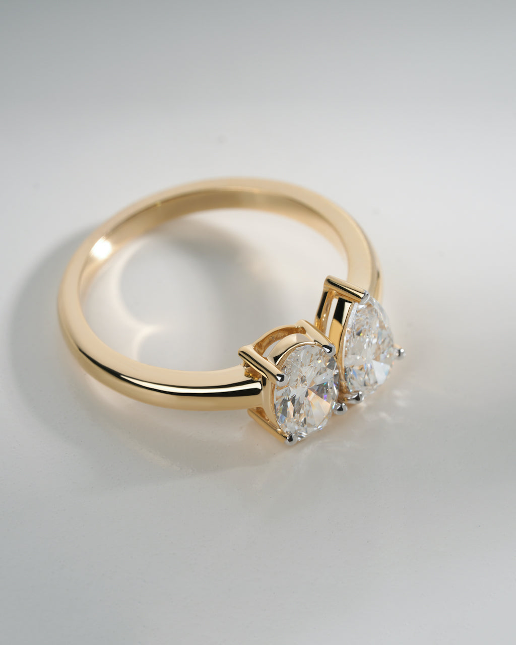 Gold ring with three diamonds on a light gray background