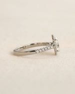 Side view of white gold oval halo engagement ring. 