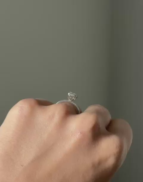 Hand wearing radiant cut diamond bezel ring in white gold.